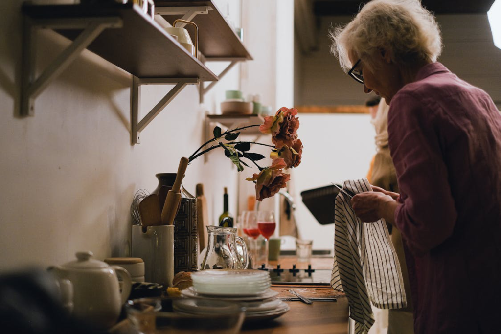 Elderly woman cleaning utensils in the kitchen