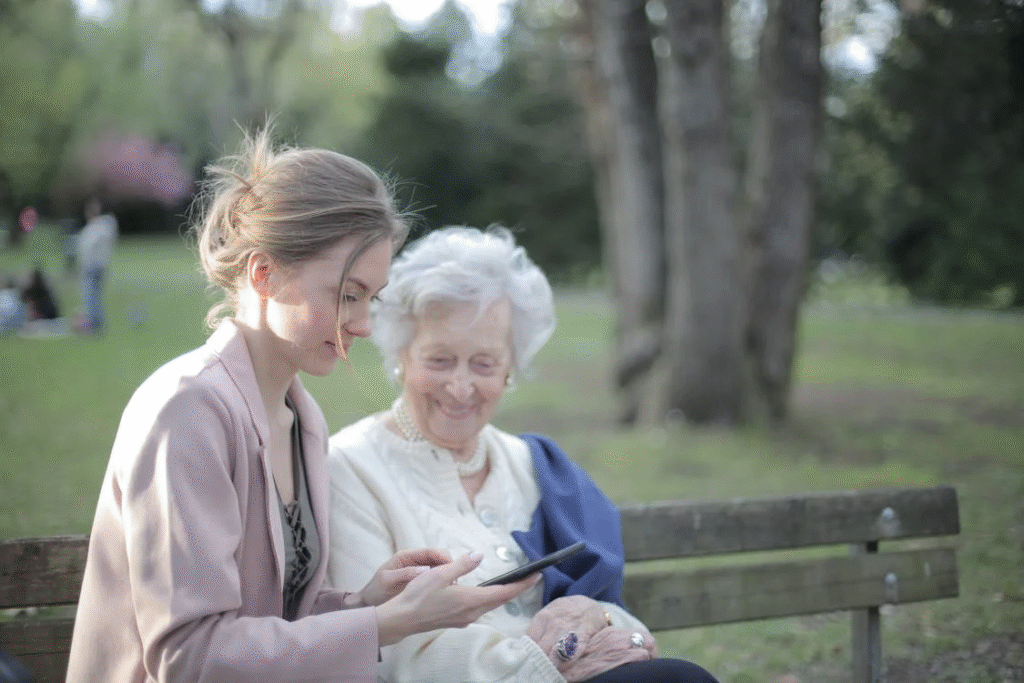 A person sitting and helping an older person with technology.
