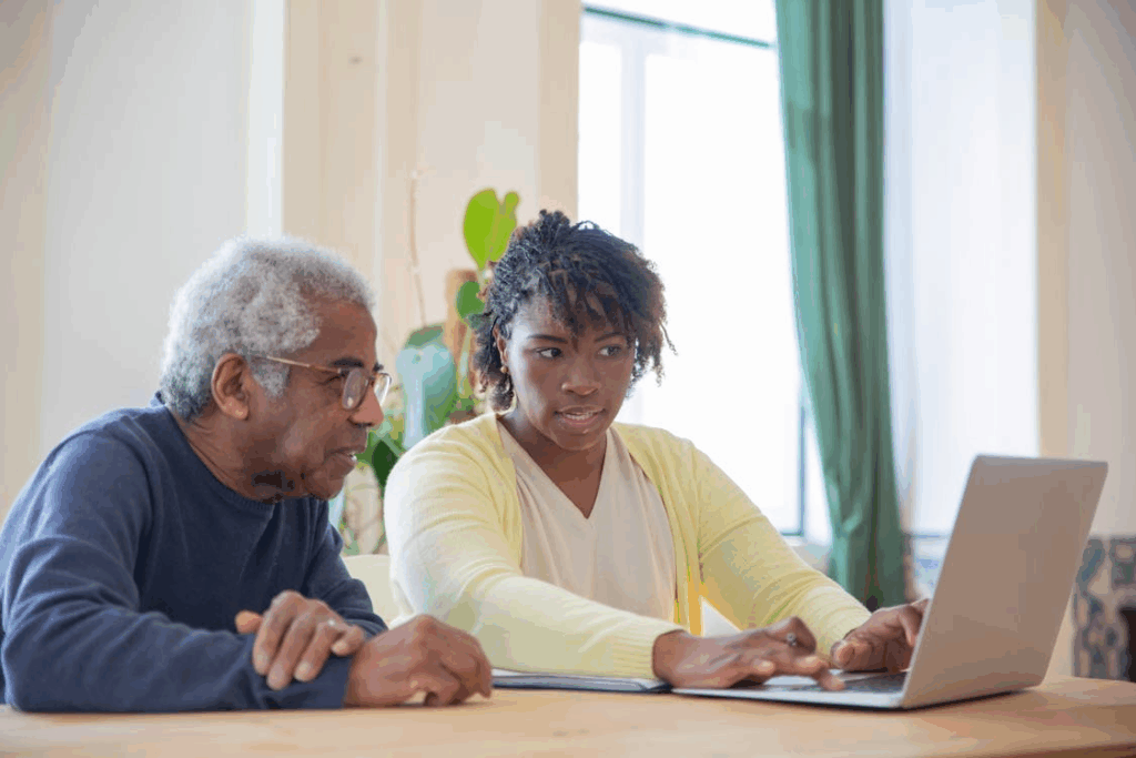 A senior using a laptop with a caregiver