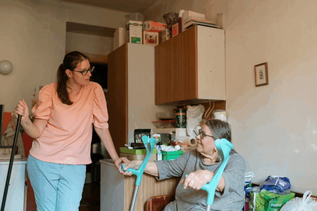 Caregiver assisting an elderly woman with mobility support using walking aids inside her home