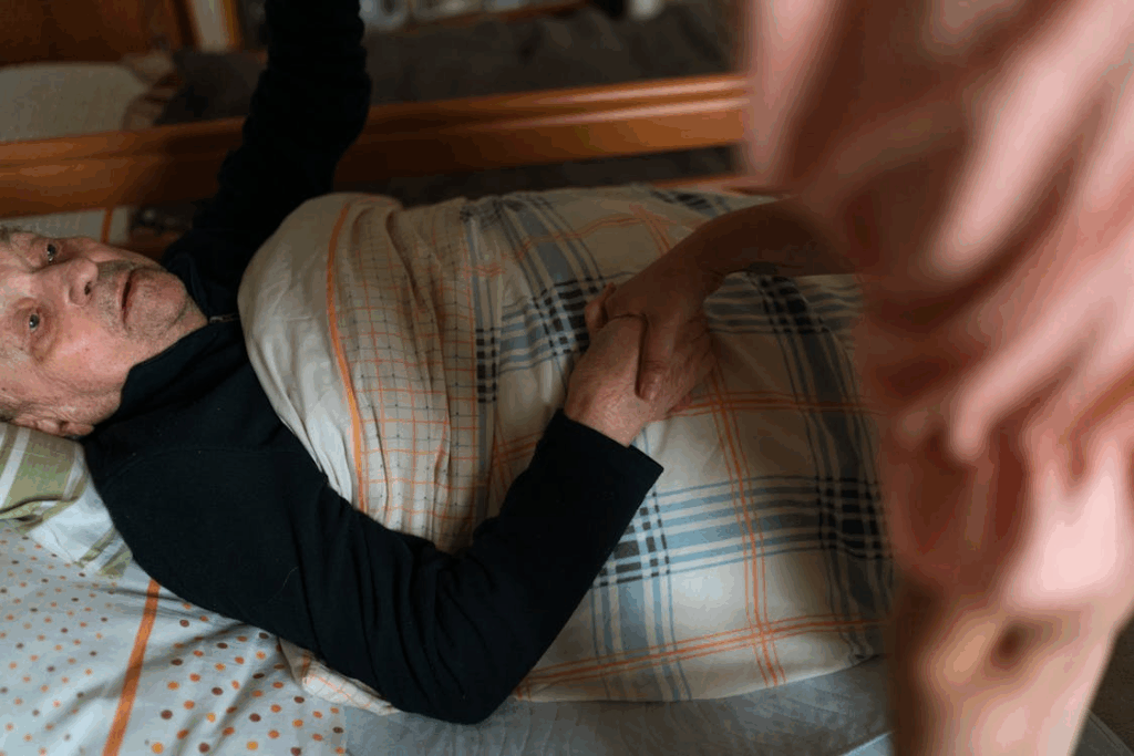 Caregiver monitoring an elderly person resting safely in bed during overnight home care support
