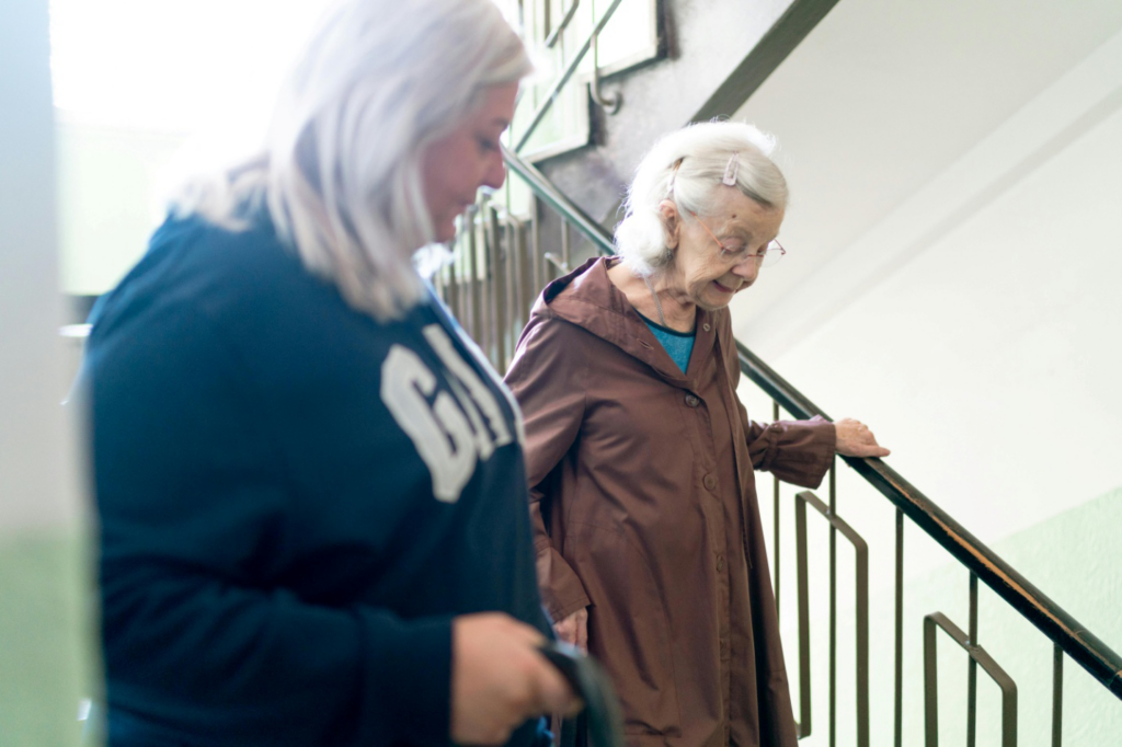 A caregiver and a senior woman walking downstairs