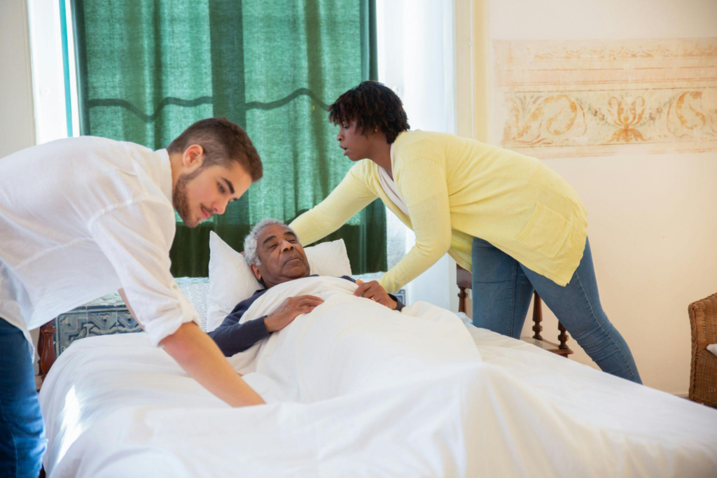 Caregivers assisting an elderly man to bed