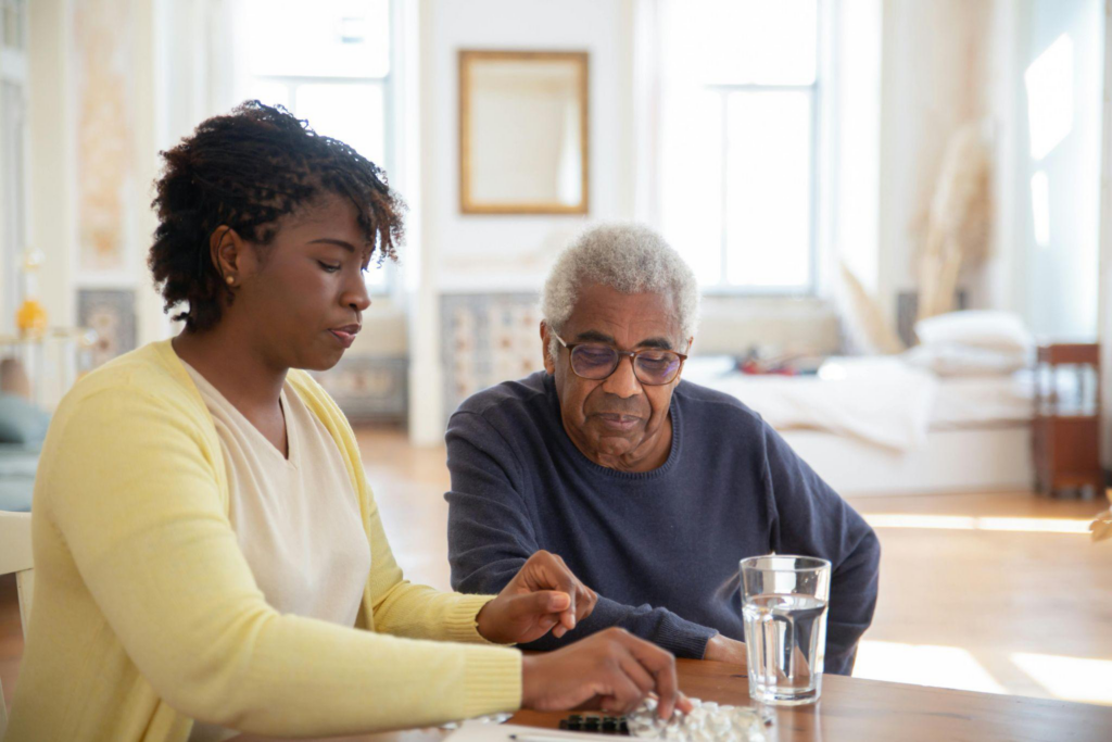 A caregiver assisting an elderly man with taking medication