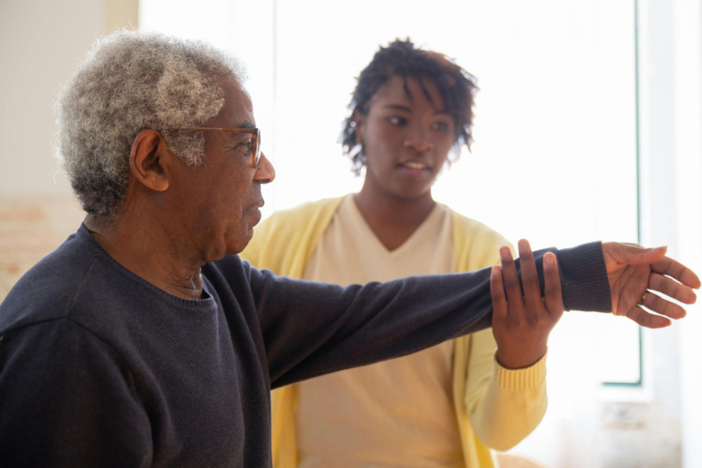 This photo shows a caregiver helping an elderly citizen exercise.