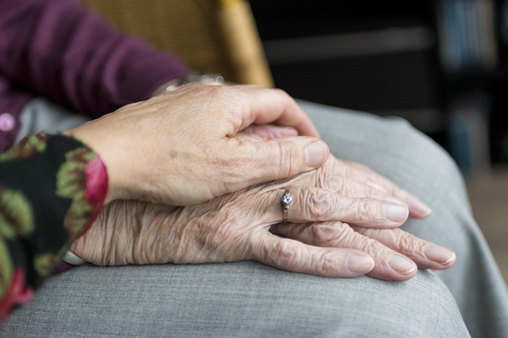 A caregiver holding an elderly person's hand