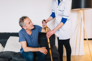 A caregiver helping an elderly person use a cane