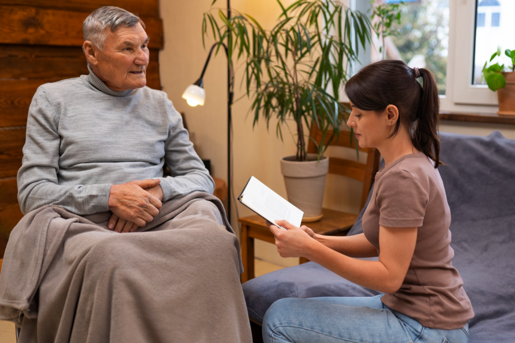A caregiver looking at a paper next to an elderly person in a wheelchair