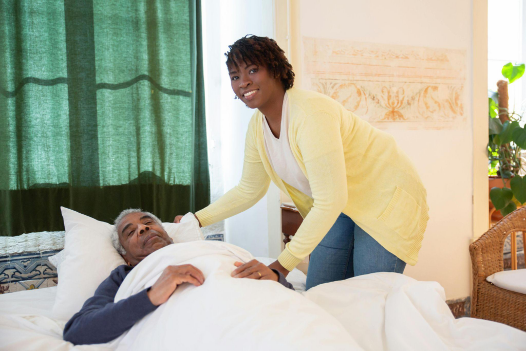 a caregiver standing by an elderly person in bed