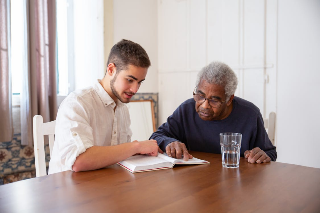 A caregiver helping an elderly person read a book